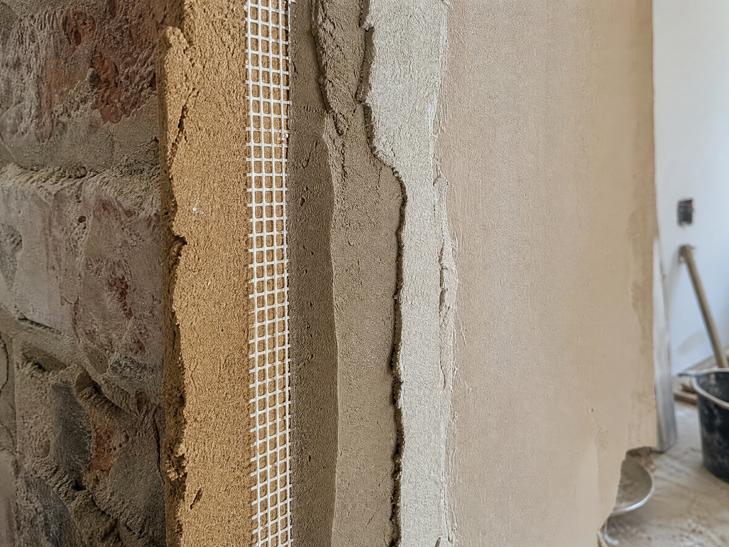 Close-up detail of materials and technique used in replastering after damp treatment — showing quality