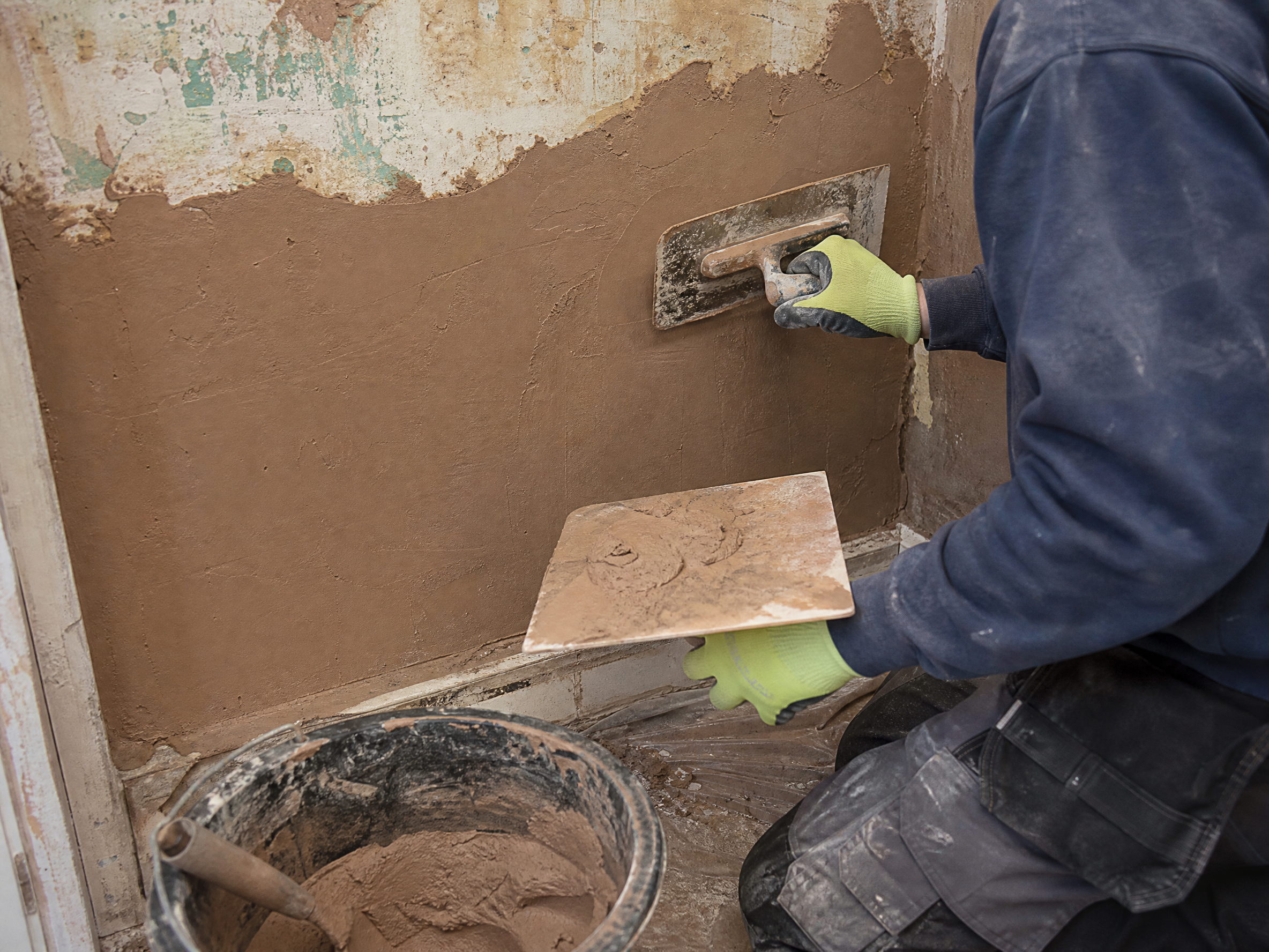 Professional installer carrying out replastering after damp treatment in a UK residential property